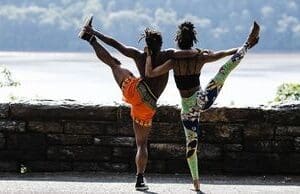 Two people doing different poses on a beach.