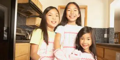 Three girls in white shirts and yellow aprons.