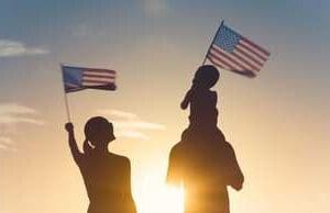 A family holding american flags in front of the sun.