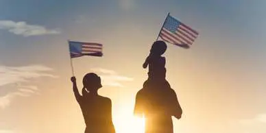 A family holding american flags in front of the sun.